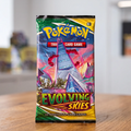 A sealed Pokémon Trading Card Game booster pack for Evolving Skies stands upright on a wooden tabletop with a blurred indoor background.