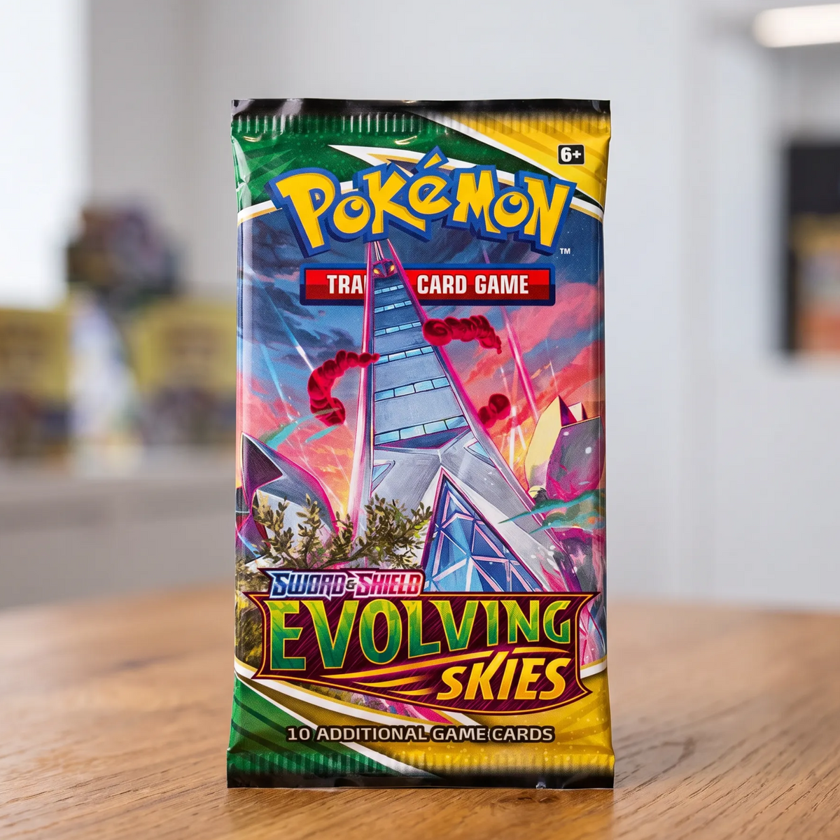 A sealed Pokémon Trading Card Game booster pack for Evolving Skies stands upright on a wooden tabletop with a blurred indoor background.