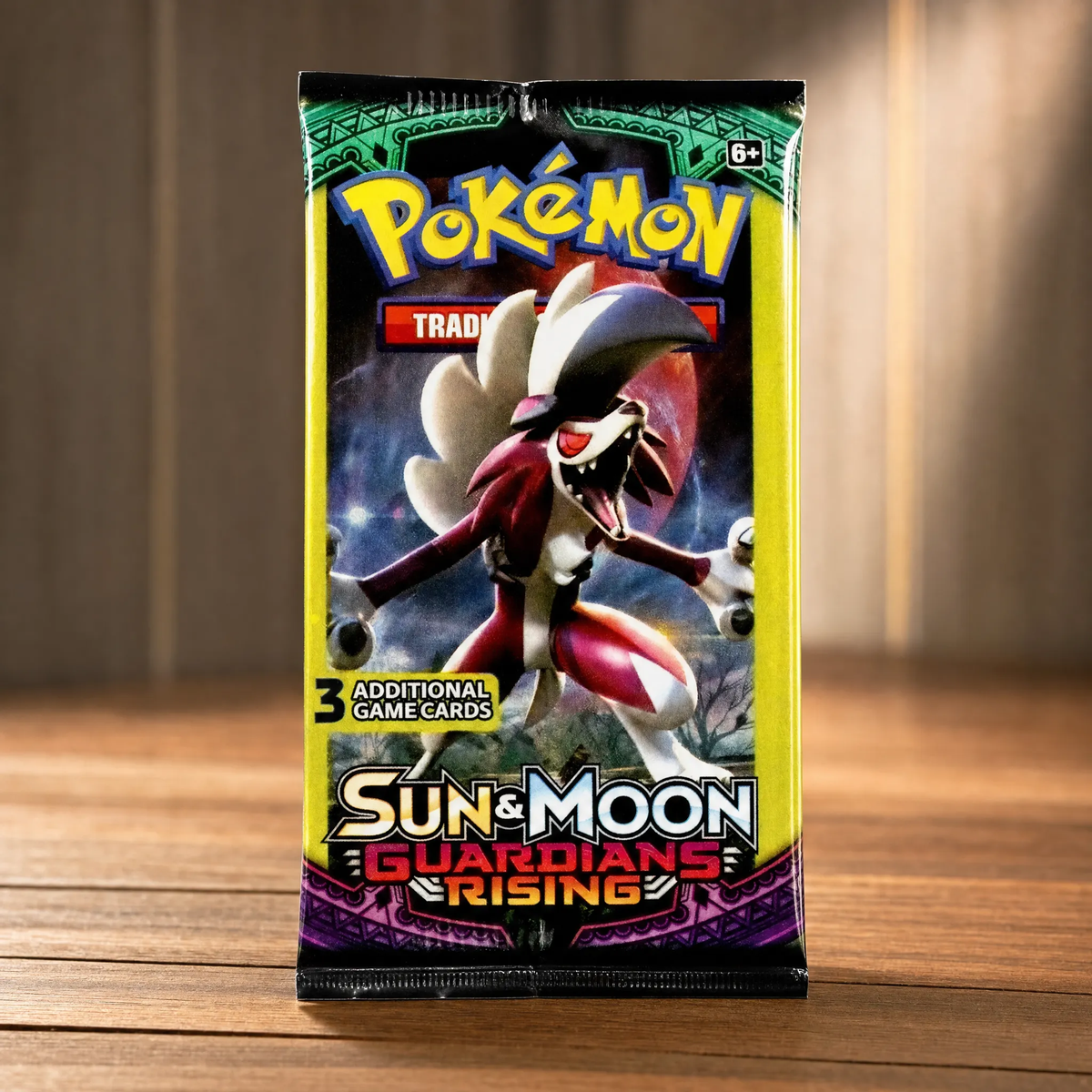 A sealed Pokémon Trading Card Game booster pack for Sun & Moon: Guardians Rising, featuring a large illustration of a red and white Pokémon on the front, standing upright on a wooden surface against a softly blurred indoor background.